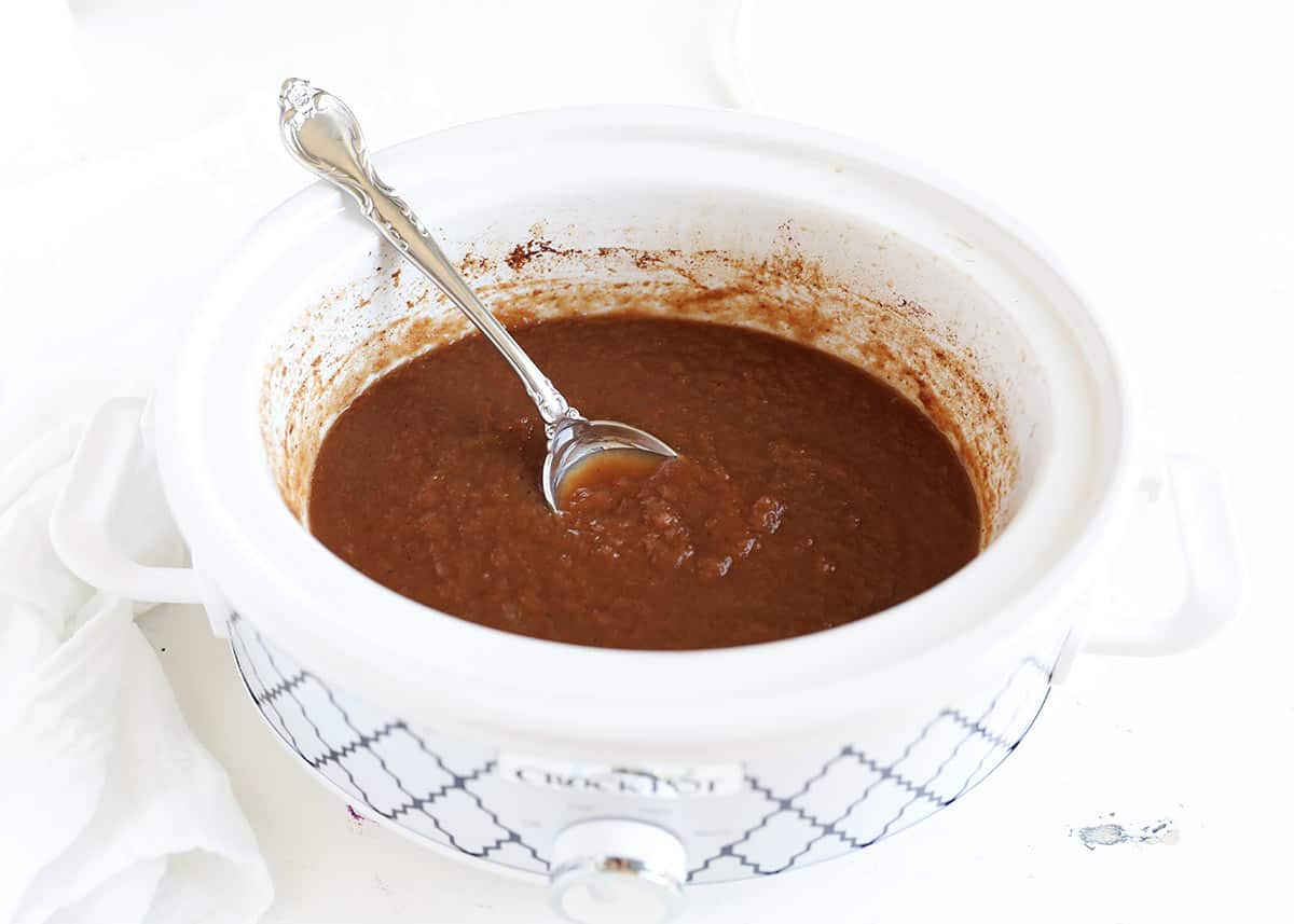 Apple butter in crock pot with spoon.