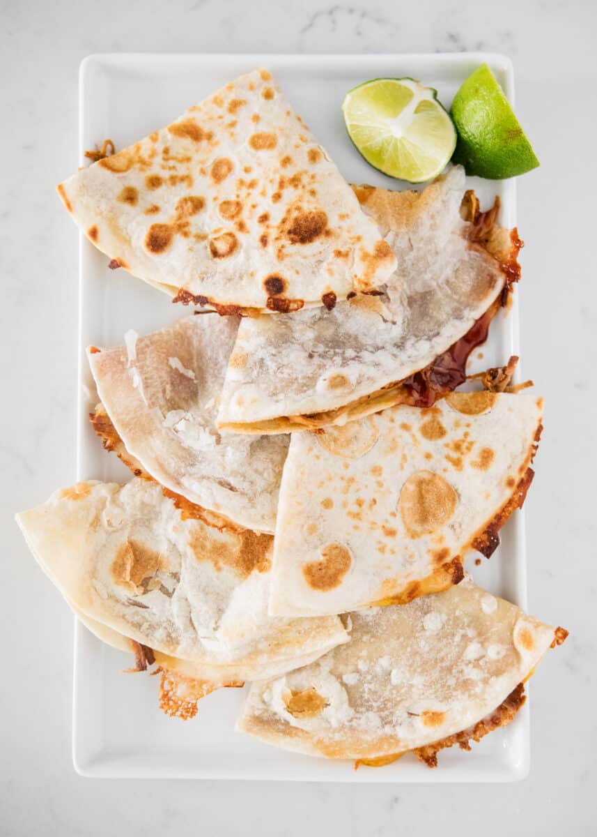 bbq pork quesadillas on a plate with a lime 