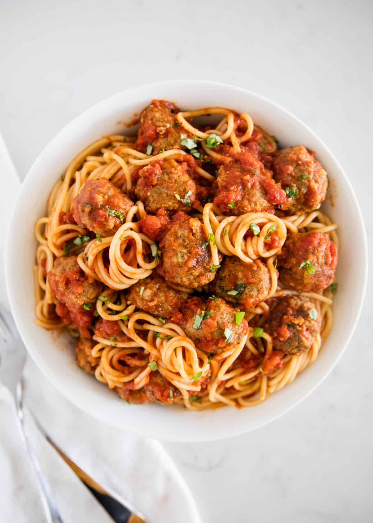 Spaghetti and meatballs on white plate.