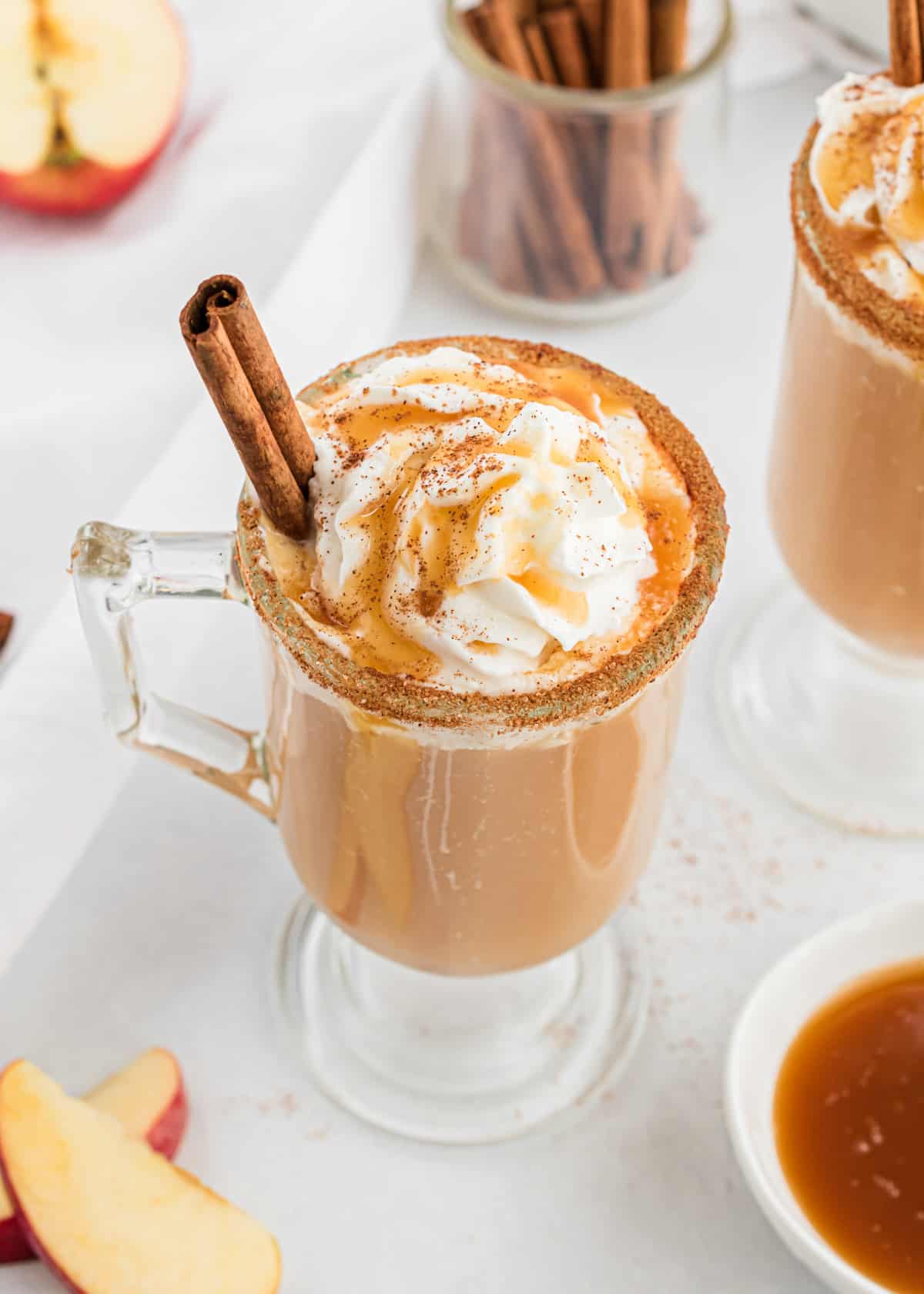 Glass cup with caramel apple cider and cinnamon.