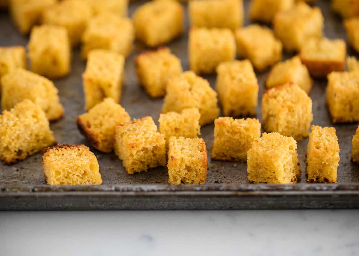 Baked cornbread croutons on pan.