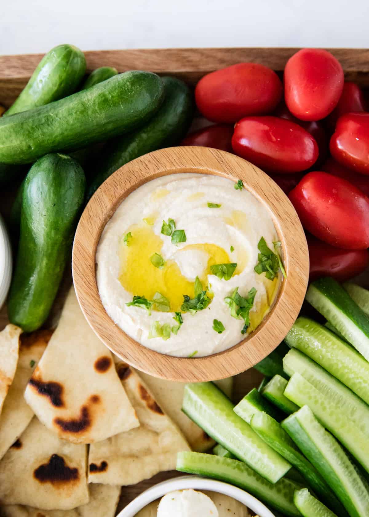 Hummus in wooden bowl with vegetables.