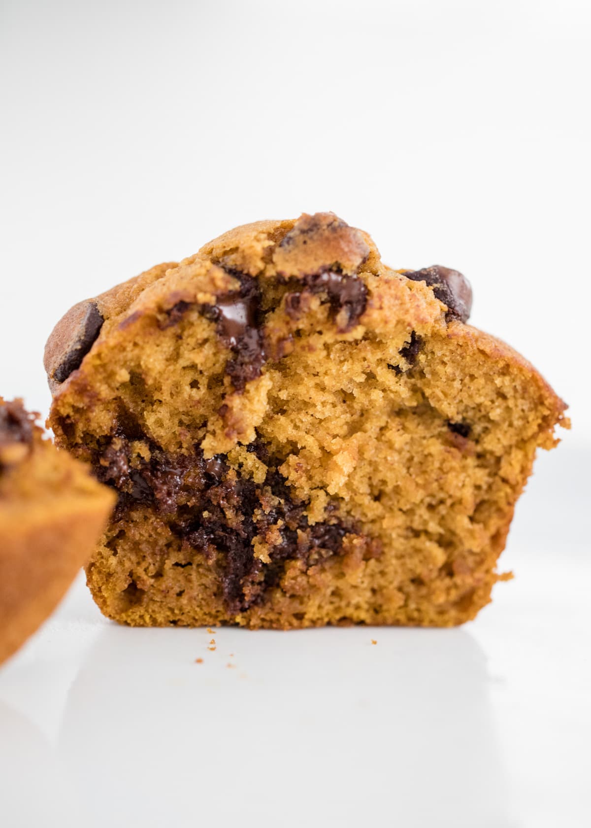 Easy pumpkin chocolate chip muffins made in just one bowl in 30 minutes. Moist, fluffy and bursting with chocolate chips. These make the perfect breakfast, snack or dessert! Bite taken from pumpkin chocolate chip muffin recipe to show moist, fluffy inside.