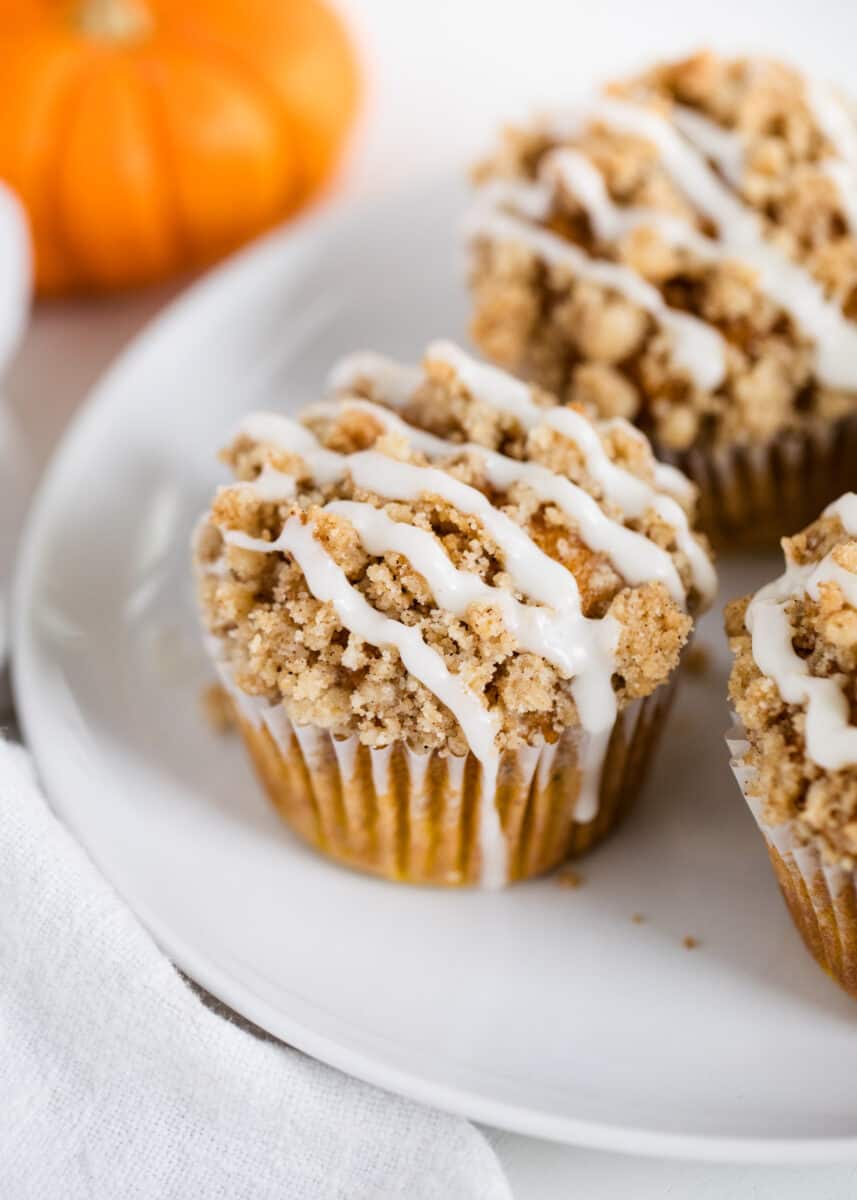 These moist pumpkin crumb muffins are made with cinnamon, applesauce and pumpkin spice. Bonus points for a mouthwatering (and slightly addictive) crumb topping. They are the perfect grab-n-go snack! crumb muffins on white plate