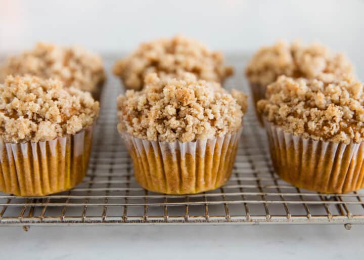 These moist pumpkin crumb muffins are made with cinnamon, applesauce and pumpkin spice. Bonus points for a mouthwatering (and slightly addictive) crumb topping. They are the perfect grab-n-go snack! pumpkin crumb muffins on cooling rack