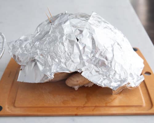 turkey resting on cutting board with foil on top