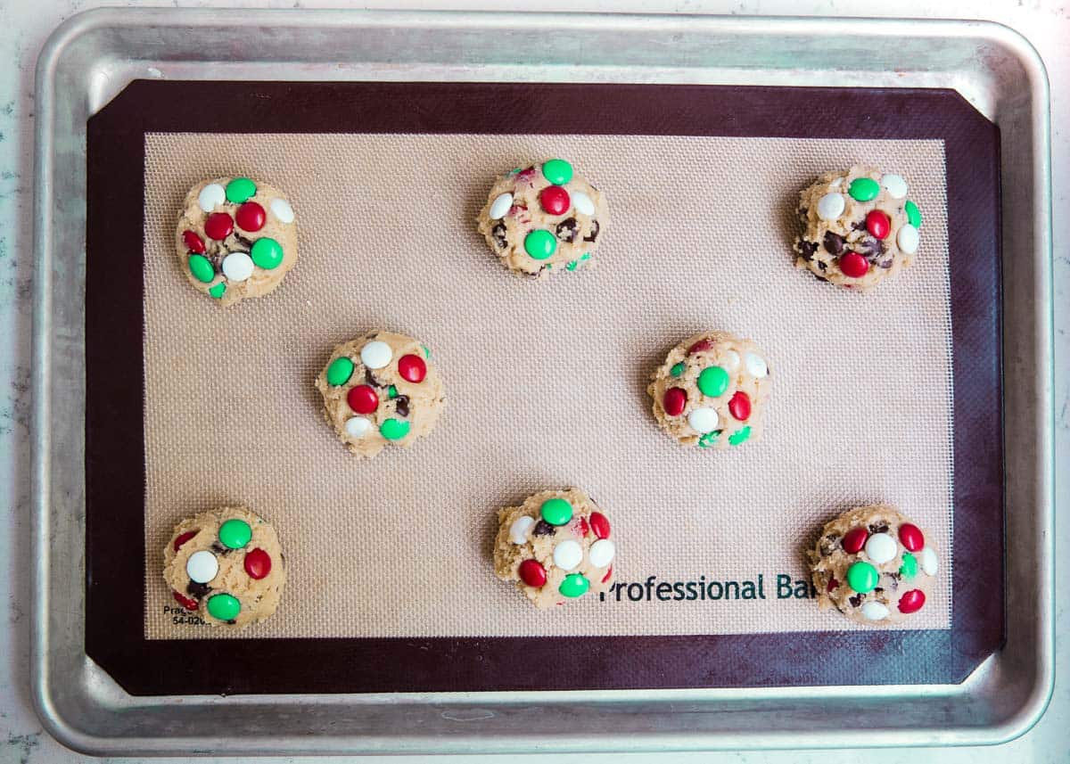 M&M Christmas cookie dough balls on pan.