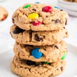 Stack of peanut butter m&m cookies on a white plate.