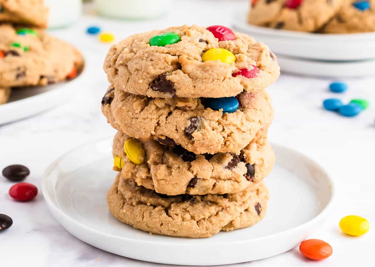 Stacked peanut butter cookies with m&m's on a white plate.