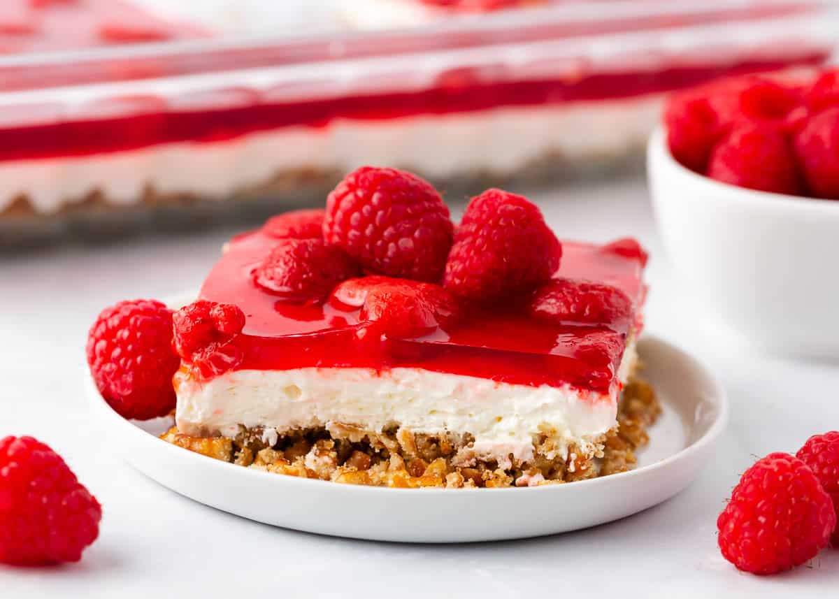 Slice of raspberry jello salad on white plate.