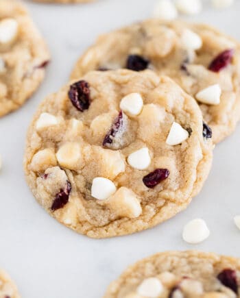 Soft and chewy white chocolate cranberry cookies studded with white chocolate chips and dried cranberries on a baking sheet.