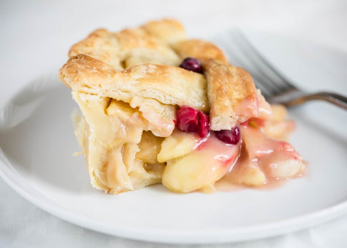 Apple cranberry pie on white plate.