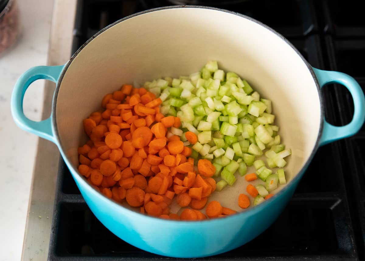 Use your leftover holiday ham to make this easy ham and bean soup! Packed full with onions, celery, carrots, ham, beans and corn. This soup is hearty, comforting and done in just 30 minutes! Carrots and celery in pot.