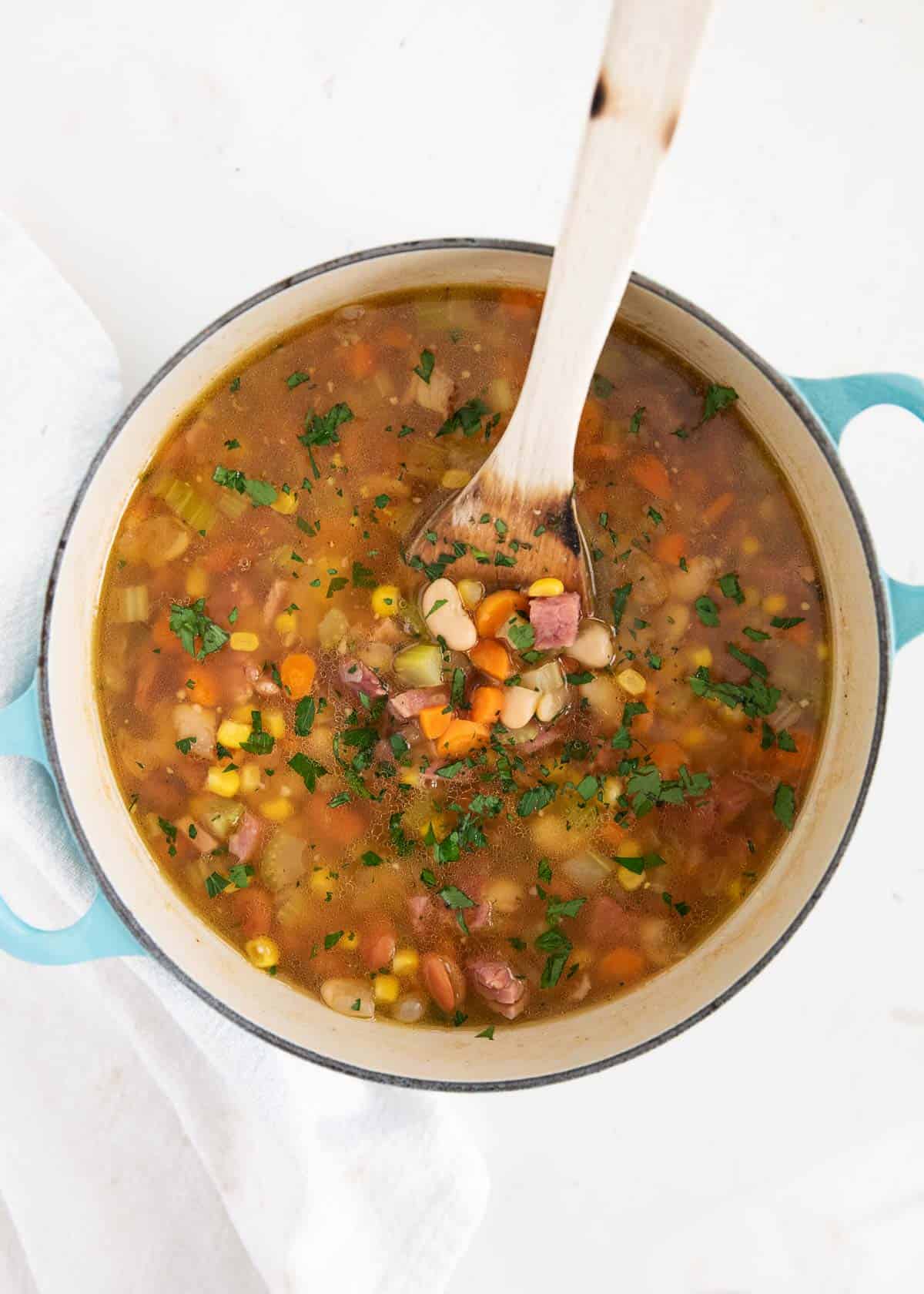 Use your leftover holiday ham to make this easy ham and bean soup! Packed full with onions, celery, carrots, ham, beans and corn. This soup is hearty, comforting and done in just 30 minutes! Ham and bean soup in pot.