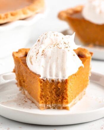 pumpkin pie with whipped cream on white plate with