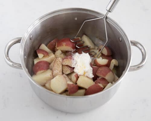 mashing red potatoes in pot