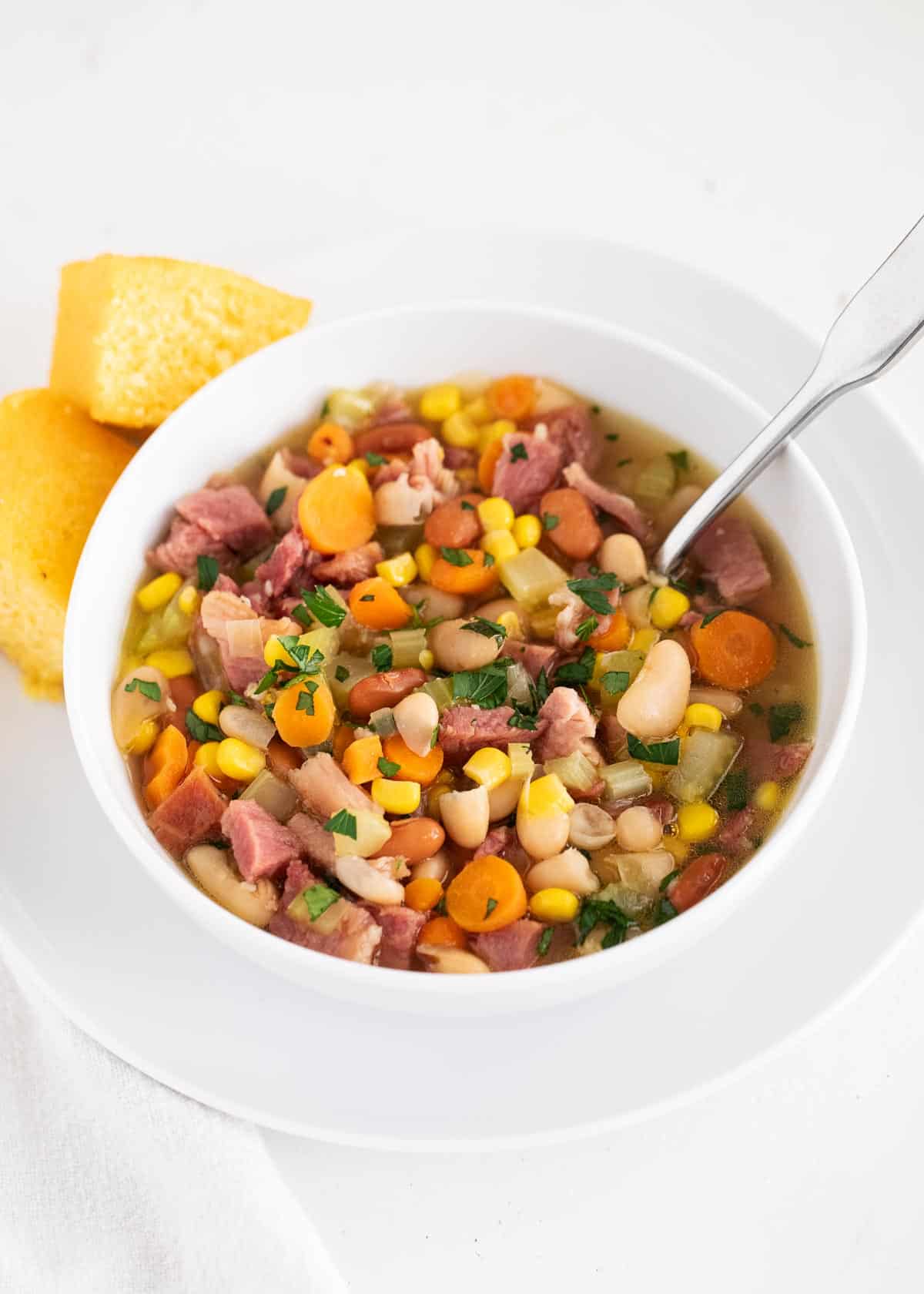 Use your leftover holiday ham to make this easy ham and bean soup! Packed full with onions, celery, carrots, ham, beans and corn. This soup is hearty, comforting and done in just 30 minutes! Ham and bean soup in bowl.