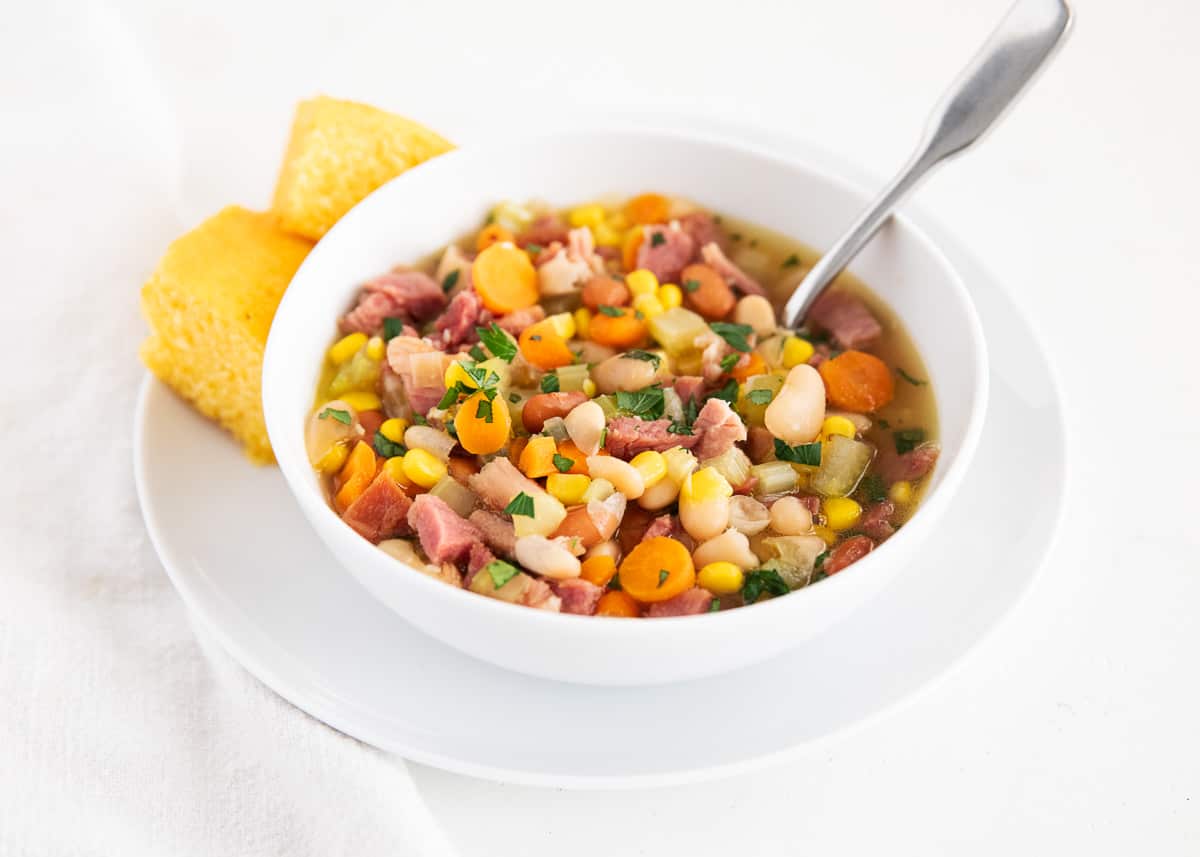 Use your leftover holiday ham to make this easy ham and bean soup! Packed full with onions, celery, carrots, ham, beans and corn. This soup is hearty, comforting and done in just 30 minutes! Ham and bean soup in bowl.