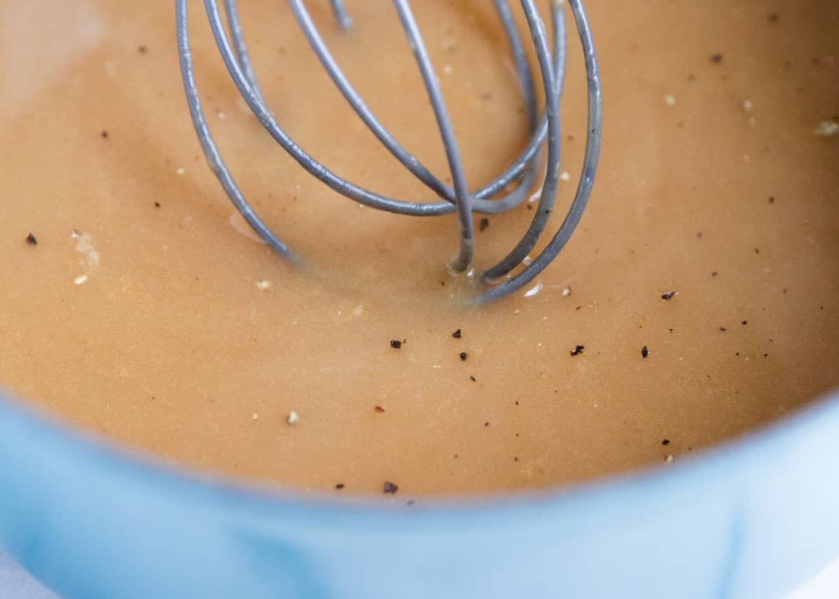 Whisking turkey gravy in pan.