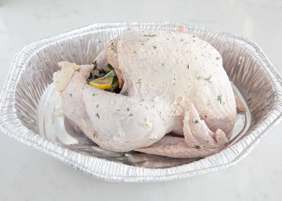 Thawed turkey with herb butter in pan.