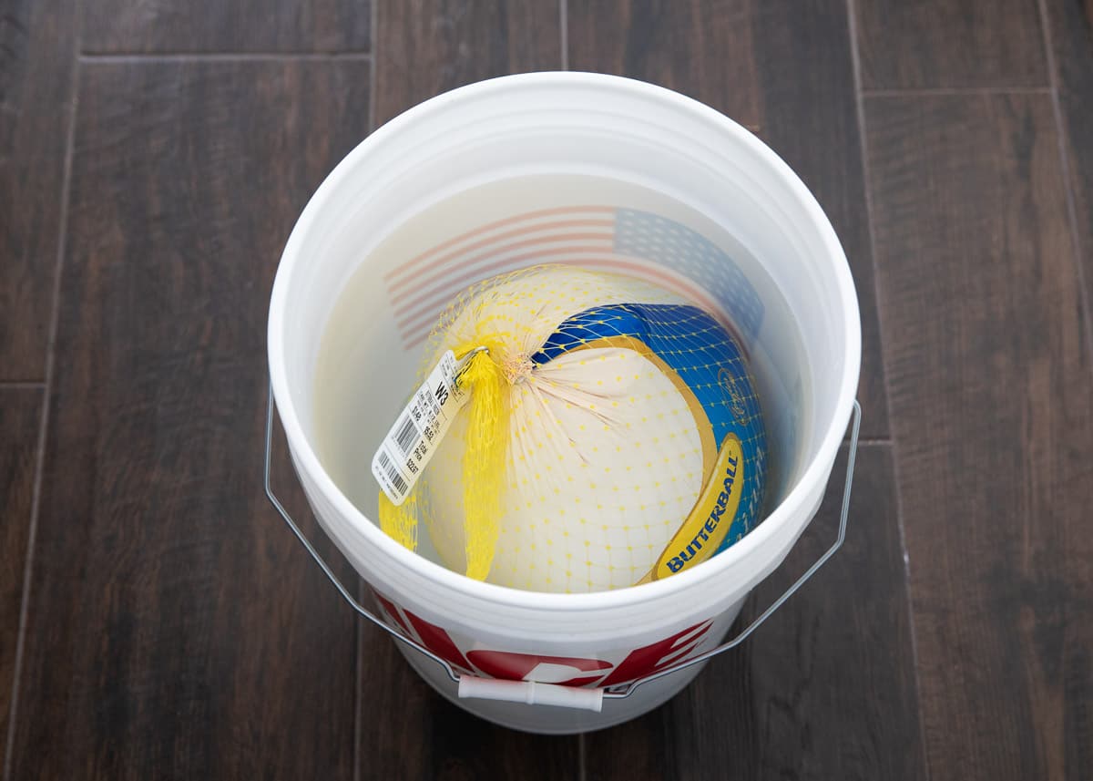 Thawing frozen turkey in bucket of water.