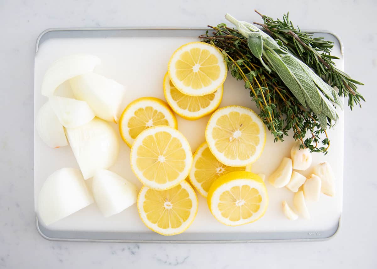 Onions, lemons and herbs on cutting board.