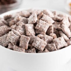 Muddy buddies made with Chex cereal, peanut butter, chocolate and powdered sugar in a bowl.