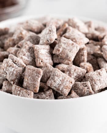 Muddy buddies made with Chex cereal, peanut butter, chocolate and powdered sugar in a bowl.