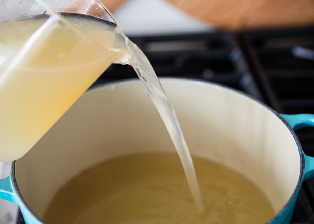 Pouring turkey stock into pot.