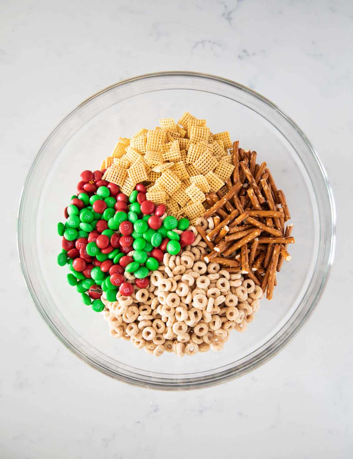Chex mix, pretzels, cheerios, and m&ms in bowl.