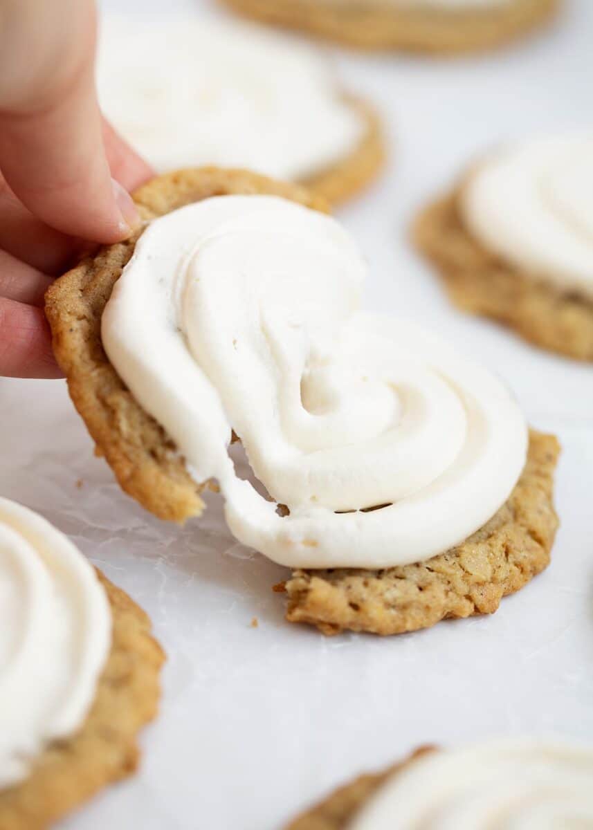 tearing apart oatmeal cookie with marshmallow frosting 