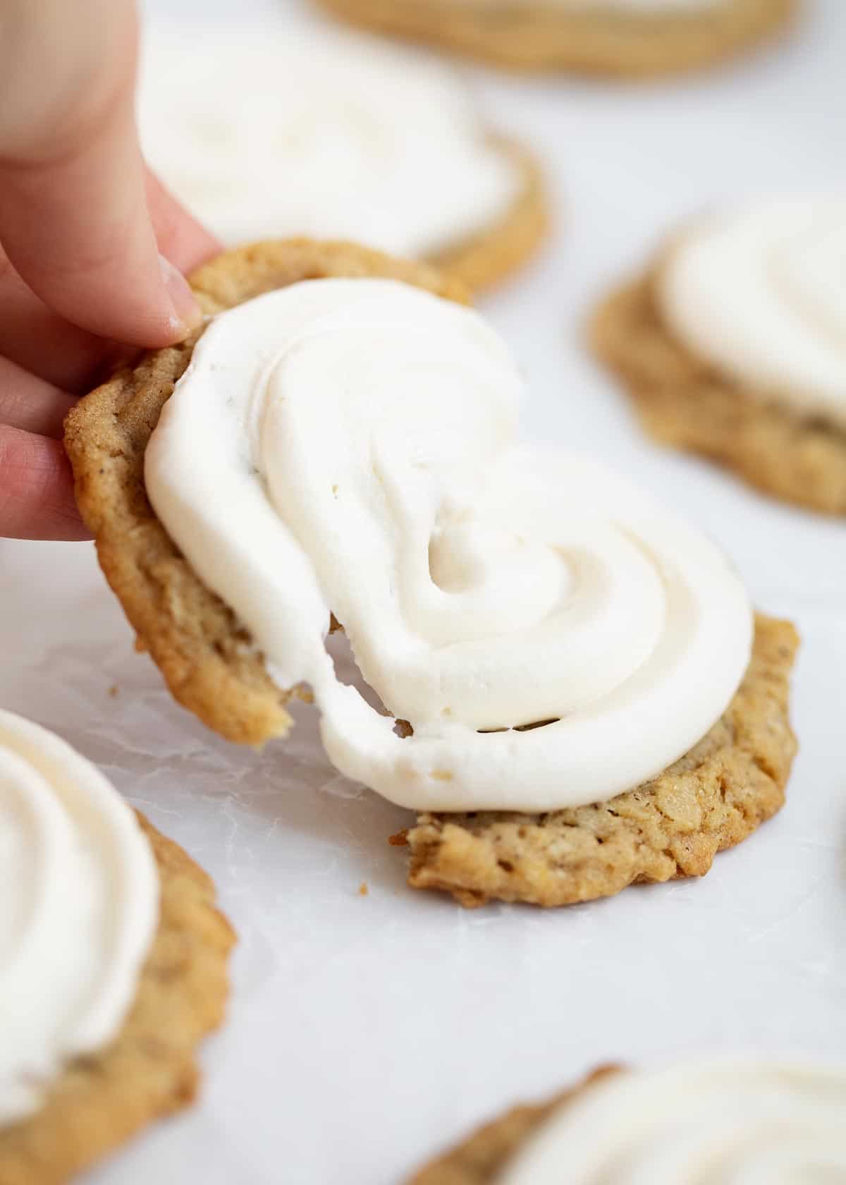 Tearing apart oatmeal cookie with marshmallow frosting.