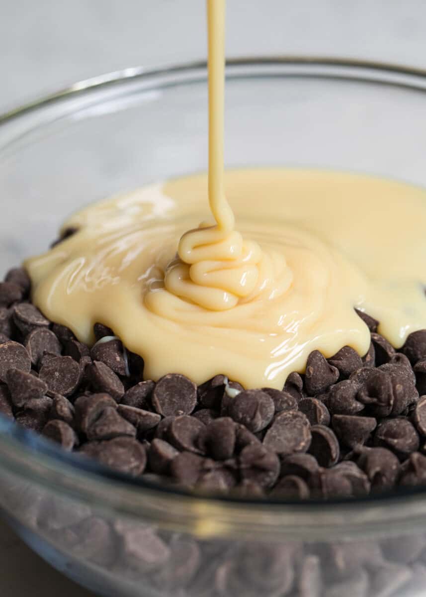 pouring sweetened condensed milk over chocolate chips