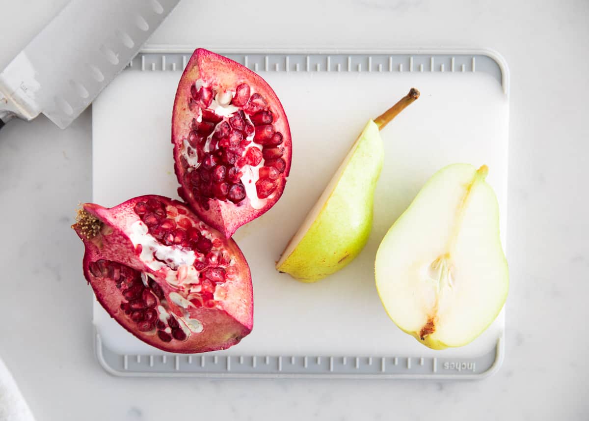 Pear and pomegranate on cutting board.