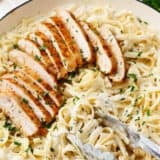 Chicken fettuccine alfredo in a white skillet.