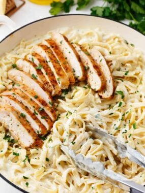 Chicken fettuccine alfredo in a white skillet.