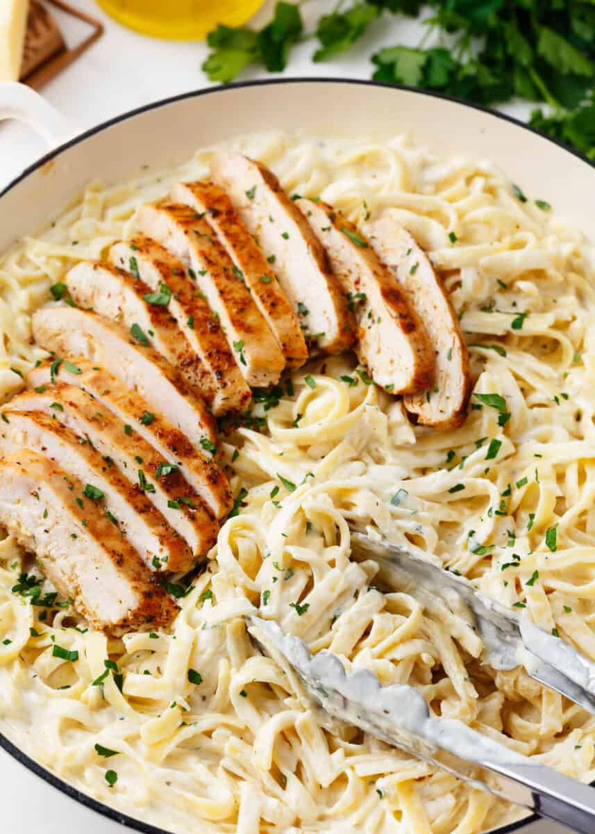 Chicken fettuccine alfredo in a white skillet.