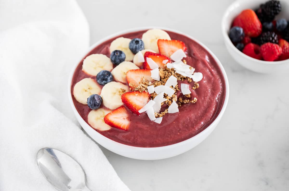 Acai smoothie in bowl with fruit and toppings.