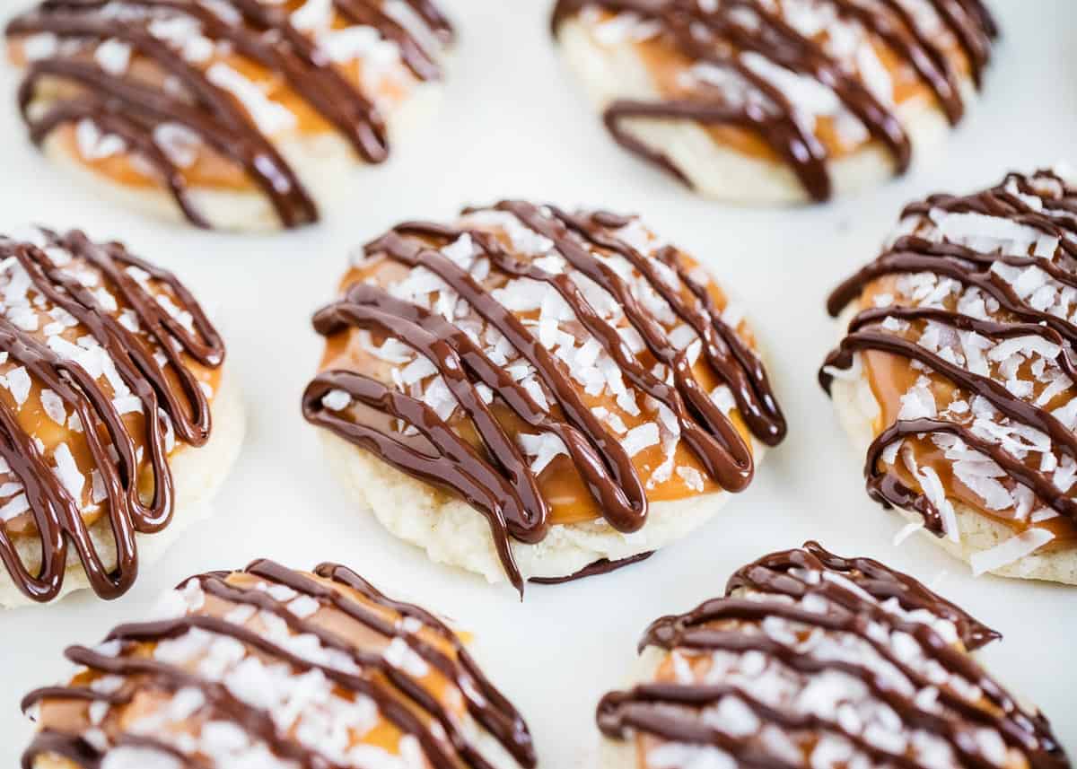 Buttery shortbread cookies topped with layers of gooey caramel, sweetened coconut and a chocolate drizzle. Every bite of these coconut caramel cookies is bursting with flavor! Coconut caramel cookies drizzled with chocolate.