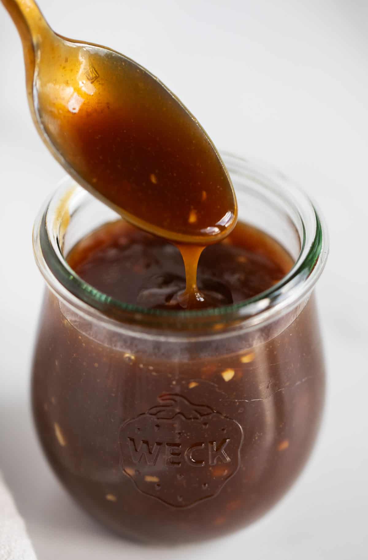 Close up of teriyaki sauce in jar with spoon.