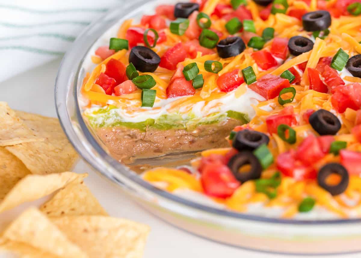 5 layer dip with toppings in glass dish.