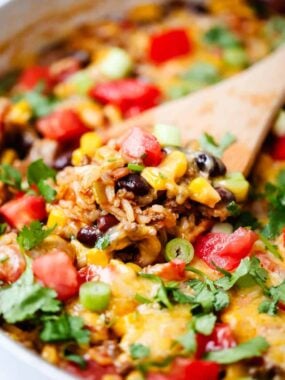 Wooden spoon getting some burrito bowl out of pot.