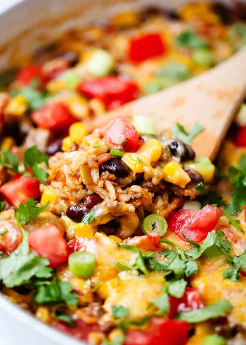 Wooden spoon getting some burrito bowl out of pot.