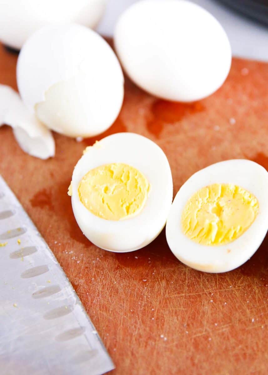 Sliced hard boiled egg on cutting board.