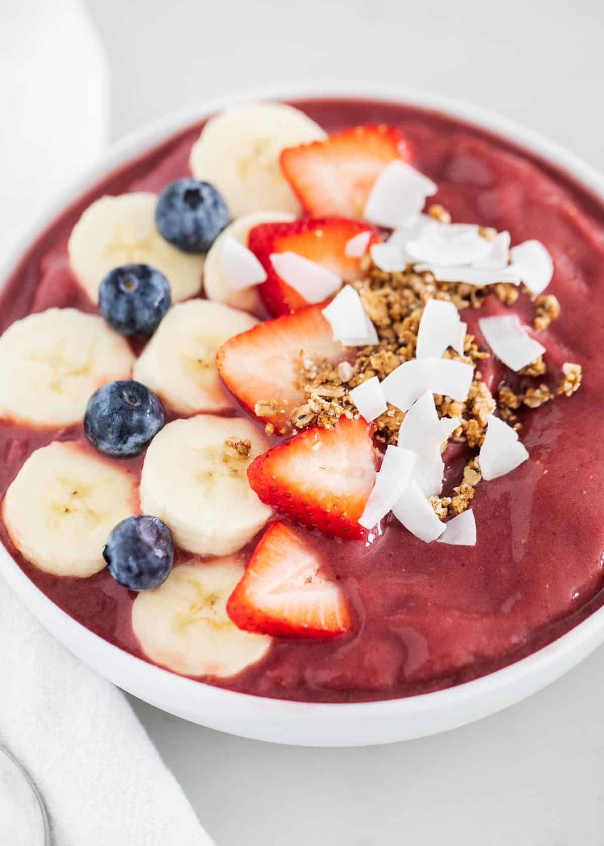 Acai smoothie in bowl with fruit and toppings.