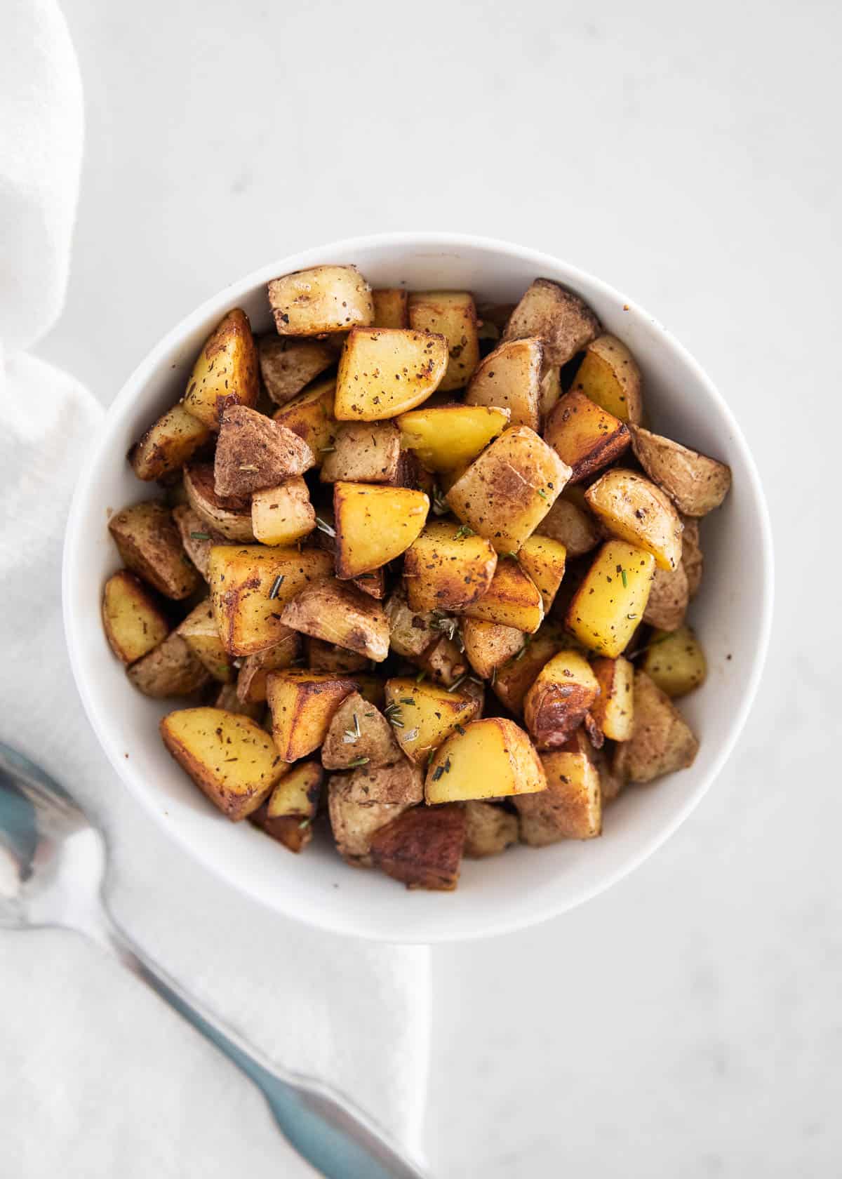 Cast iron skillet potatoes in white bowl.