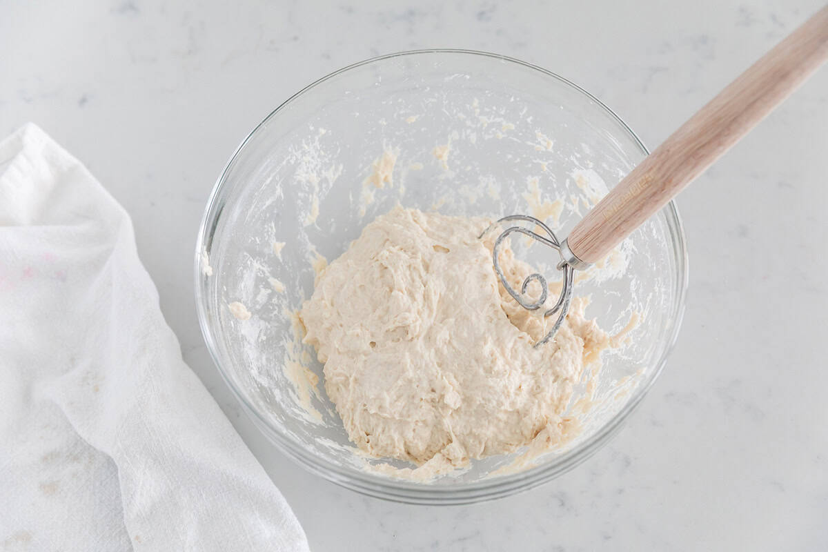No knead bread dough mixed with dough whisk in a glass bowl until shaggy and sticky.