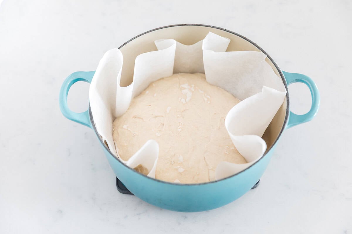 No knead bread dough placed in a parchment-lined Dutch oven before baking.
