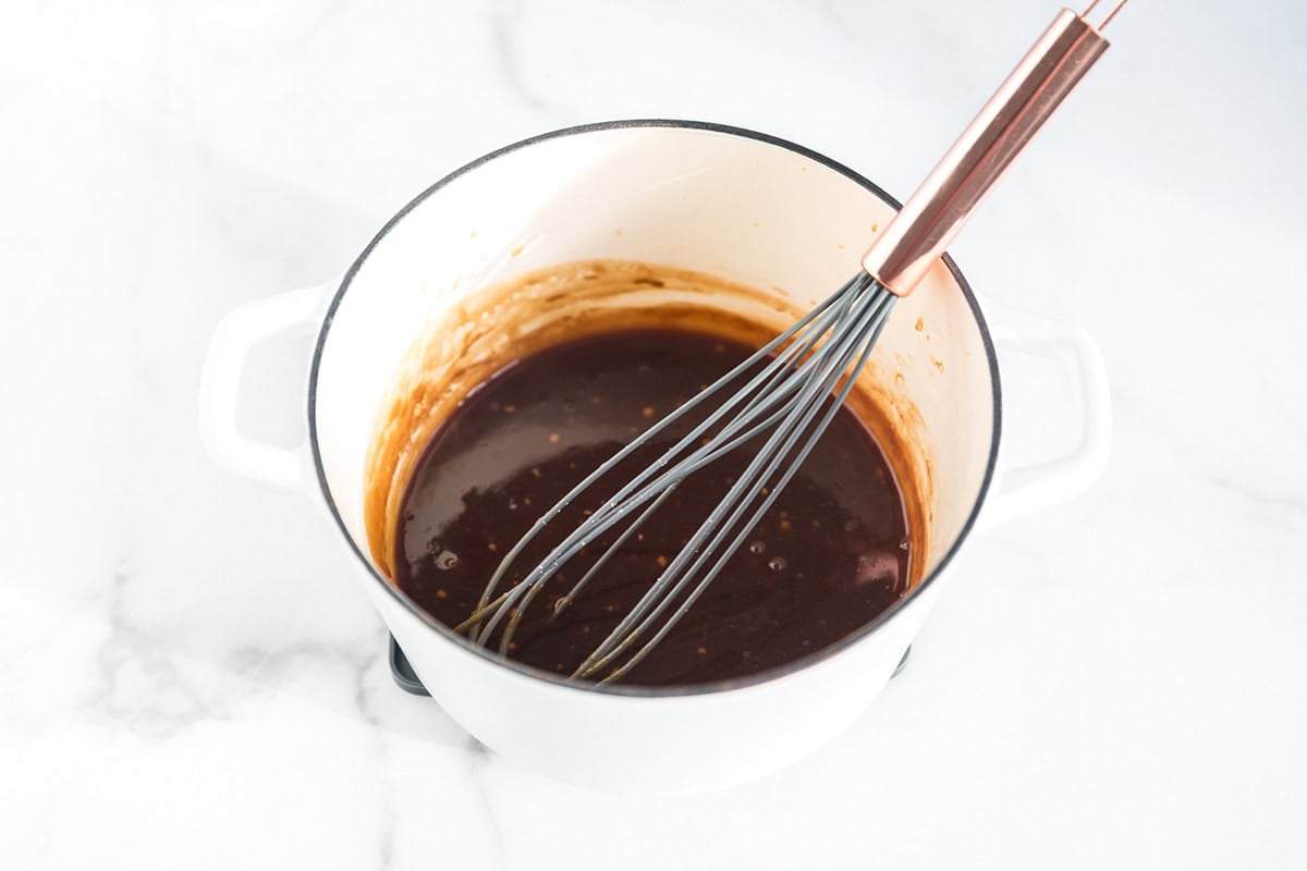 Teriyaki sauce recipe ingredients in a sauce pan with whisk.