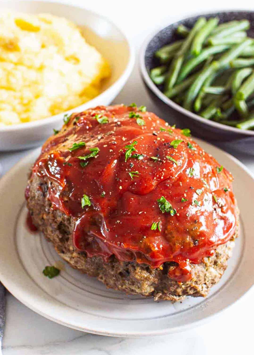 Meatloaf on plate with mashed potatoes and green beans.
